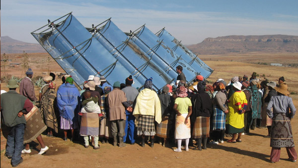 group of about 40 people standing outside looking at sail-like invention