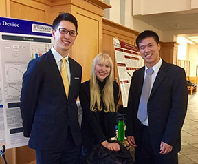 Members of the Spasticity Quantification Device team standing in front of a presentation about their device